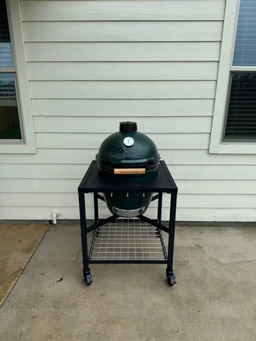 Green barbecue grill on a stand outside a house